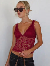 Woman wearing a red lace top and sunglasses against a plain background